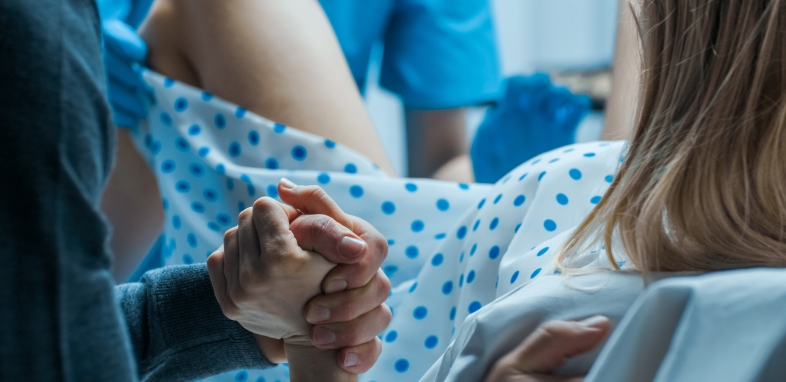 Birth Injury woman giving birth holding hand in delivery room
