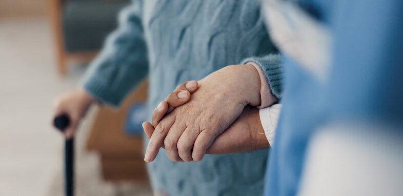 Nursing Home Abuse close up of elderly person holding hands with caretaker