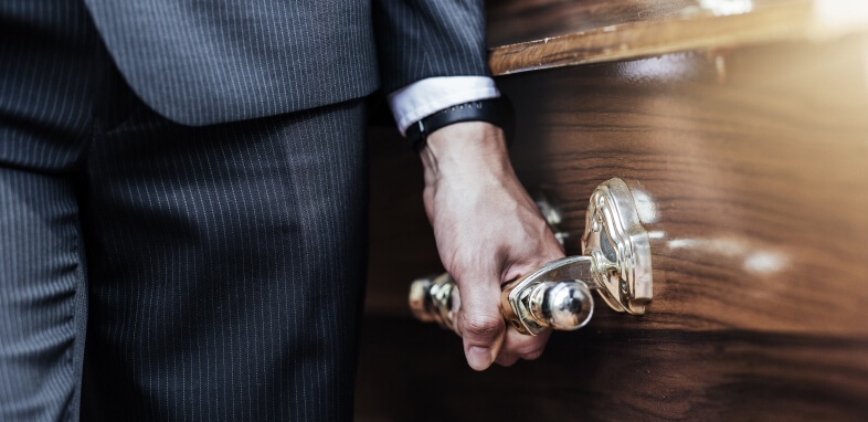 Wrongful Death close up of man in suit holding casket handle